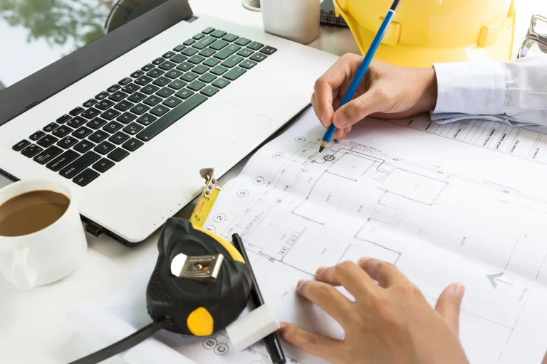 Contractor reviewing a blueprint with a pencil and ruler