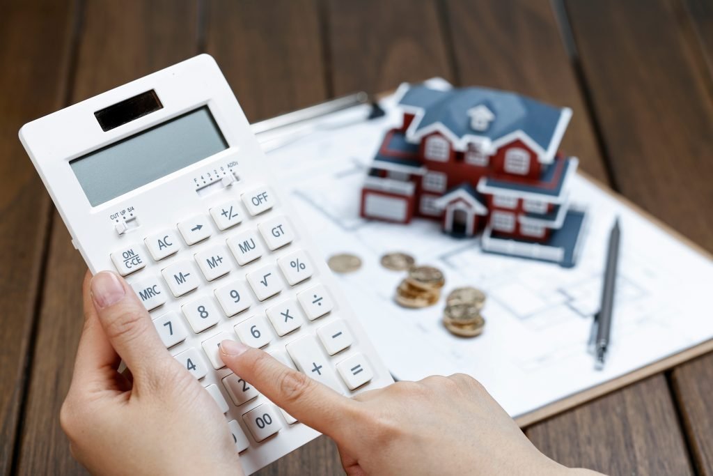 Calculator and house model showing how construction estimate costs are worked out