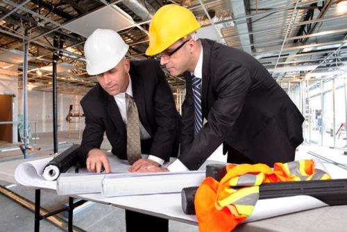 men wearing hardhats looking at a blueprint